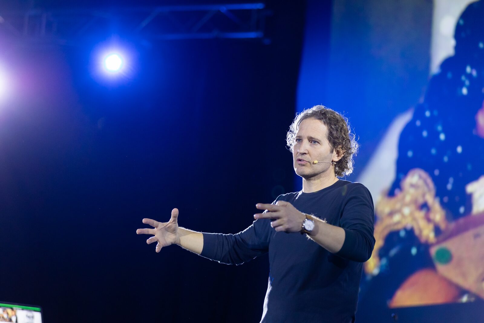 SalvaROCK speaking expressively on a blue-lit stage